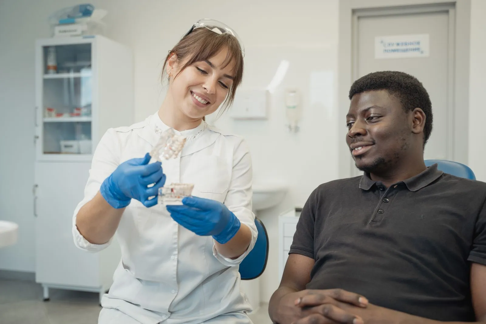 A dentist showing a patient a model of teeth during a consultation