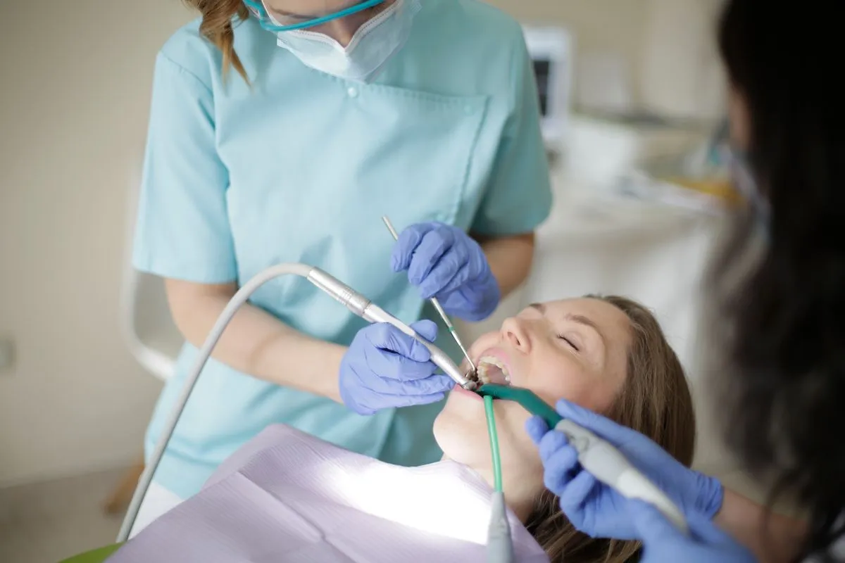 A hygienist cleaning a patient's teeth in a bright treatment room